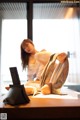 A woman sitting on top of a bed next to a laptop computer.