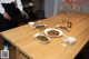 A man standing behind a wooden table with plates of food on it.