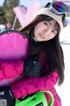 A young woman holding a snowboard in the snow.