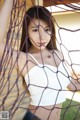 A woman in a white top is posing behind a net.