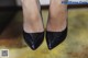 A close up of a woman's legs wearing black shoes.