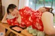 A woman in a red kimono laying on a wooden table.