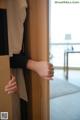 A woman is peeking out from behind a wooden door.