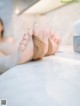 A woman laying on top of a bed with her feet up.