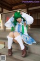 A woman with green hair sitting on a wooden bench.