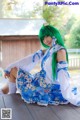 A woman with green hair sitting on a wooden deck.