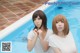 Two young women standing next to a swimming pool.