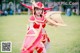 A woman dressed in a red and gold costume holding a sword.