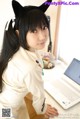 A woman in a cat ears headband sitting at a desk with a laptop.