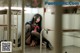 A woman sitting on the floor in a jail cell.