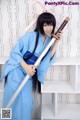 A woman in a blue kimono holding a sword.