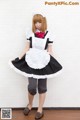 A woman dressed in a maid outfit posing for a picture.