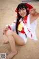 A woman in a red and white outfit sitting on a beach.