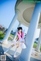 A woman in a pink and white outfit posing for a picture.