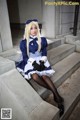 A woman in a blue and white dress sitting on some steps.