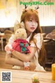 a woman sitting at a table holding a stuffed animal