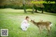 A little girl kneeling down next to a deer in a field.