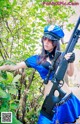 A woman in a blue uniform holding a rifle.