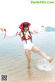 A woman in a white bathing suit and red hat is standing in the water.