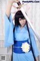 A woman in a blue kimono holding a sword.