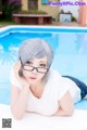 A woman laying on the ground next to a swimming pool.