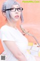 A woman in a white shirt and glasses holding a shower head.