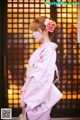 A woman in a pink kimono with a flower in her hair.