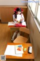 A woman sitting at a desk in a classroom.