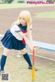 A woman in a school uniform holding a baseball bat.