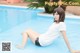 A woman sitting on the edge of a swimming pool.