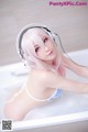 A woman in a bathtub with headphones on.