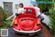 A couple of women sitting on top of a red car.