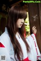 A woman in a white and red kimono leaning against a wooden door.