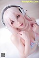 A woman with pink hair wearing headphones and a bikini.