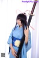 A woman in a blue kimono holding a sword.