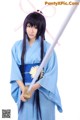 A woman in a blue kimono holding a sword.