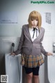 A woman in a school uniform standing next to a urinal.