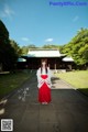 A woman in a red and white kimono standing in front of a building.