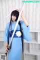 A woman in a blue kimono holding a sword.