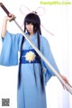 A woman in a blue kimono holding a sword.