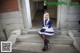 A woman in a blue and white dress sitting on some steps.