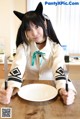 A woman sitting at a table with a plate and fork.