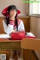 A woman sitting at a desk with a red purse.