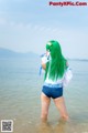 A woman with long green hair standing in the water.