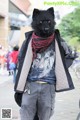 A man in a wolf mask is walking down the street.