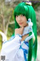 A woman with long green hair holding a stuffed animal.