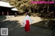 A woman in a red and white kimono standing in front of a building.