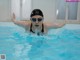 A woman in a swimming cap and goggles swimming in a pool.