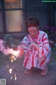 A little girl in a kimono holding a sparkler.