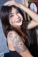 A woman with a tattoo on her arm posing for a picture.